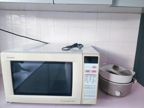 a microwave with a pair of glasses on top of it at Ipoh Tambun pool villa 5br 18pax bbq mahjong in Tambun