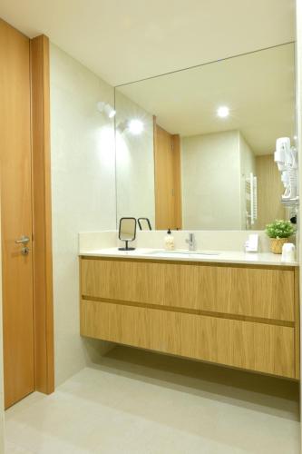 a bathroom with a sink and a large mirror at BUTEKO HOUSE AL in Miranda do Douro