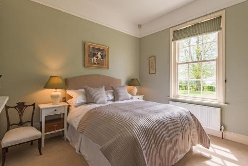a bedroom with a bed and a chair and a window at Telegraph House by inspirestays-com in Chichester