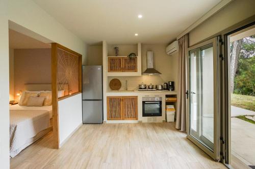 a bedroom with a bed and a kitchen with a refrigerator at Forest Resort Suites Skiathos in Troulos