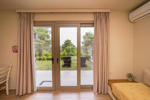 a bedroom with sliding glass doors with a view of a yard at Forest Resort Suites Skiathos in Troulos