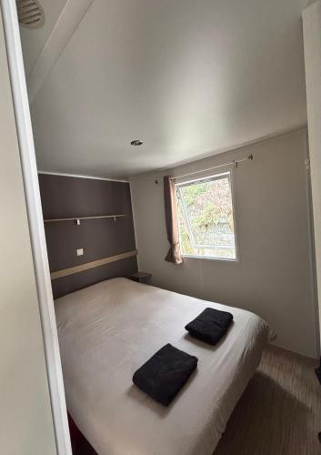 - une chambre avec un lit et 2 serviettes noires dans l'établissement Mobil home climatisé le bois dormant 4 etoiles, à Saint-Jean-de-Monts