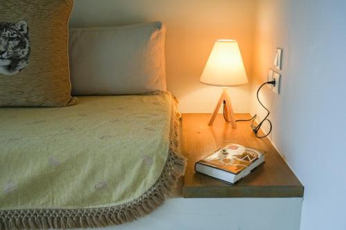 a bed with a lamp and a book on a table at Forest Resort Suites Skiathos in Troulos