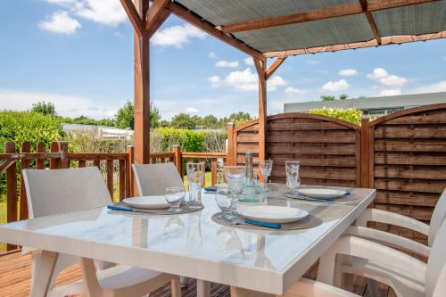 une table et des chaises blanches sur une terrasse en bois dans l'établissement Beau mobile home avec terrasse, à Carnac