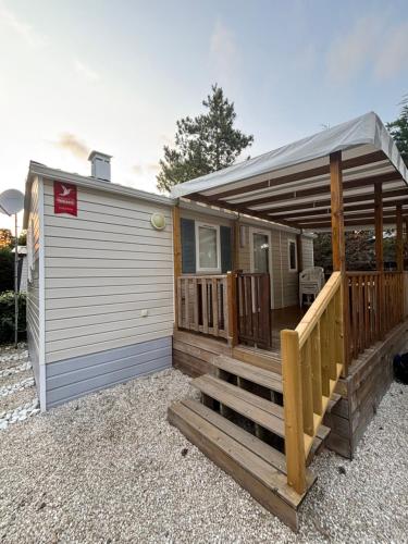 une petite maison avec un porche et une terrasse dans l'établissement Mobil home climatisé le bois dormant 4 etoiles, à Saint-Jean-de-Monts