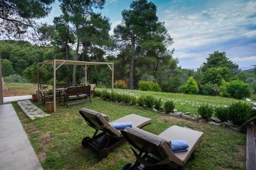a backyard with two chairs and a picnic table at Forest Resort Suites Skiathos in Troulos
