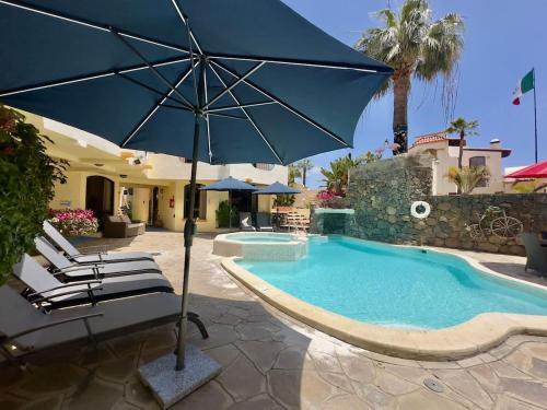 a pool with chairs and an umbrella next to a house at Puerto Nuevo Surf Villa Flores 2BR with pool in Raulis