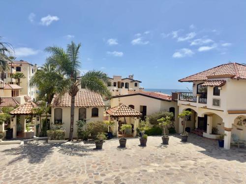 a group of buildings with palm trees in a courtyard at Puerto Nuevo Surf Villa Flores 2BR with pool in Raulis