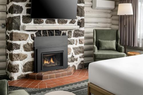 a living room with a fireplace and a chair at Mont Gabriel, Sainte-Adèle, a Tribute Portfolio Resort in Sainte-Adèle