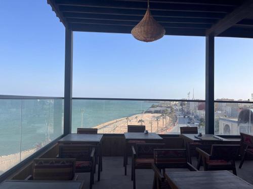 a restaurant with tables and chairs and a view of the beach at Medina Hotel Dakhla in Dakhla