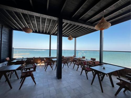 an empty restaurant with tables and chairs and the ocean at Medina Hotel Dakhla in Dakhla