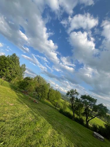 a green field with benches and a cloudy sky at Siedlisko pod Tatrami - agroturystyka in Maruszyna