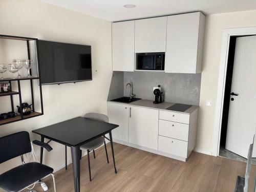 a kitchen with white cabinets and a black table at Studio Flat by the sea in Melnragė