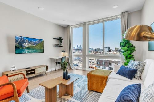 a living room with a white couch and a large window at Lux 2BD with KINGS - Pier Views - Near Fishtown! in Philadelphia
