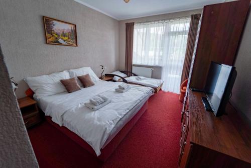 a bedroom with a bed and a flat screen tv at Penzión Alpský dom in Vitanová