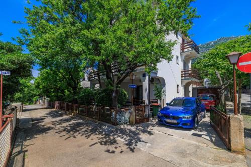 a blue car parked in front of a house at Apartments Bono in Karlobag