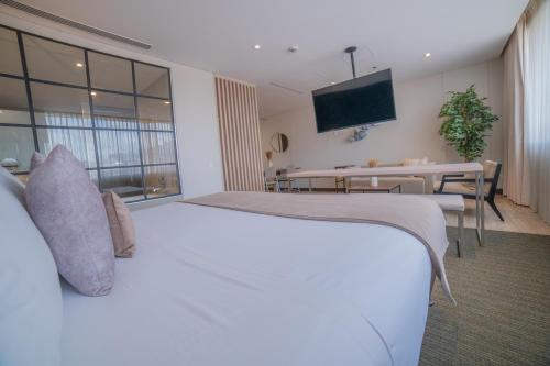 a hotel room with a large white bed and a table at SHG Liv Zona G Hotel in Bogotá
