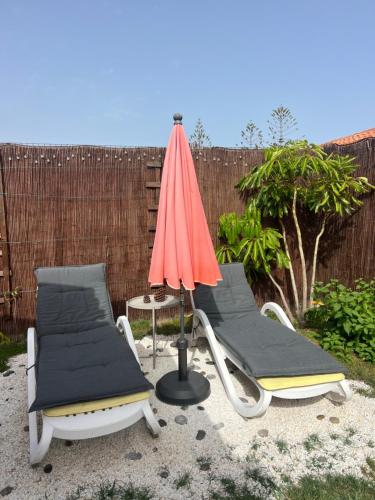 two lounge chairs and an umbrella on a patio at BuzzStays: 1-Bed Bungalow, Garden, Near Yumbo & Beach in Maspalomas