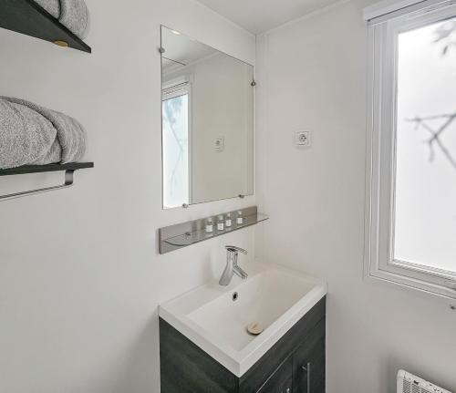 une salle de bain blanche avec un lavabo et un miroir dans l'établissement Nomadys, à Litteau