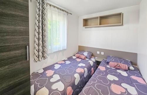 une petite chambre avec deux lits et une fenêtre dans l'établissement Nomadys, à Litteau