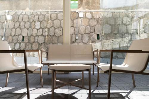 three chairs and a table in front of a stone wall at Stabiae Suite&Spa Sorrento Coast Suites in Castellammare di Stabia