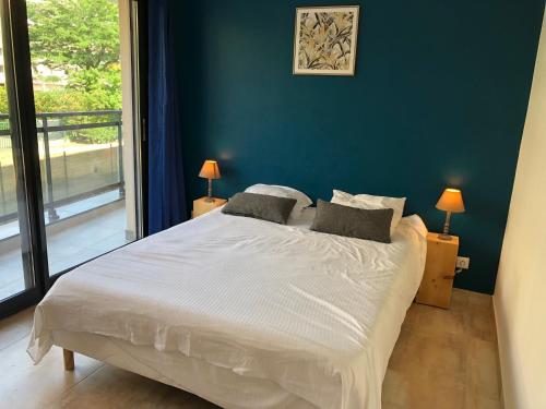 - une chambre avec un grand lit blanc et un mur bleu dans l'établissement Le Saint-Joseph, à Fréjus