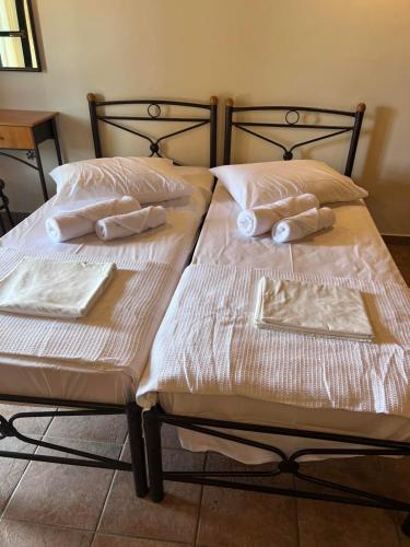 two beds with white sheets and pillows on them at Famprika Volissos in Chios