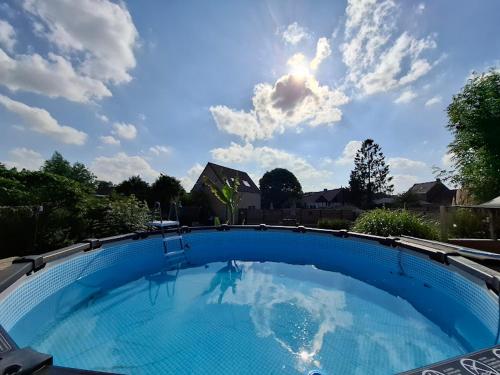 a large blue swimming pool with the sky in the background at De Boskouter - studio - op het platteland - hondvriendelijk - gastvrij in Geraardsbergen