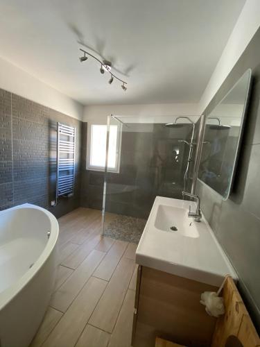 La salle de bains est pourvue d'une baignoire blanche, d'un lavabo et d'une douche. dans l'établissement Quiet house in provence, à Lauris