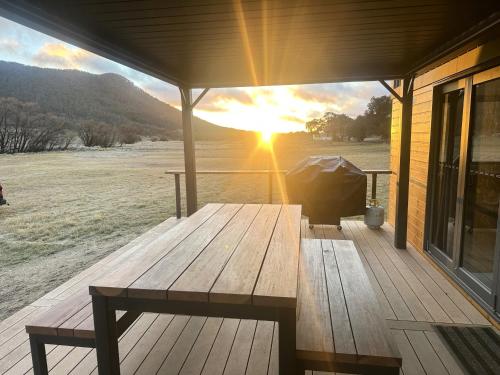 a wooden picnic table on a porch with the sunset at Wombat Creek Tiny House in Crackenback