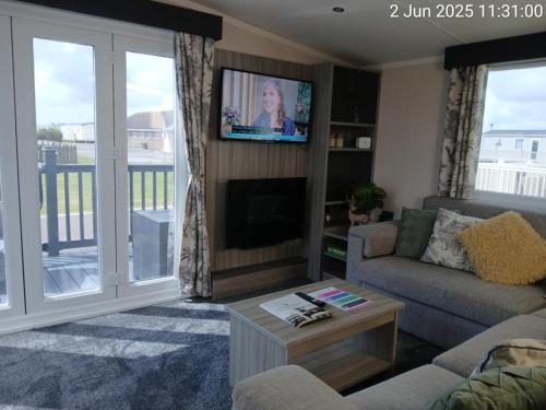 a living room with a couch and a tv at Thrillseeker - next to Fantasy Island, Ingoldmells, dog friendly in Skegness