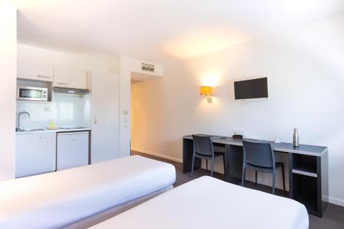 a hotel room with two beds and a kitchen at All Suites Appart Hôtel - Aéroport Paris-Orly Rungis in Rungis