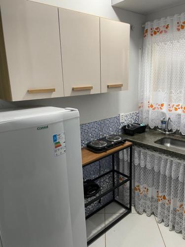 a kitchen with white cabinets and a sink at Kitnet aconchegante in Rio das Ostras