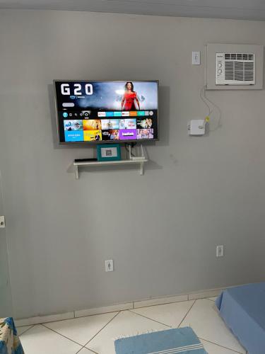 a flat screen tv on a wall in a living room at Kitnet aconchegante in Rio das Ostras