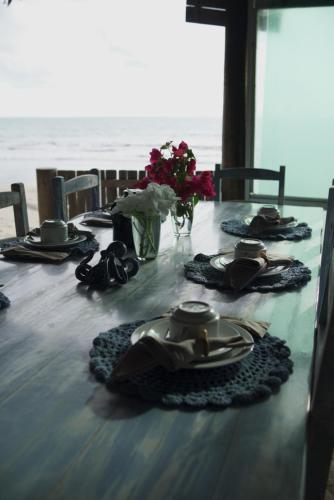 a table with chairs and plates and flowers on it at Beijo Mar Beach Club in Tibau