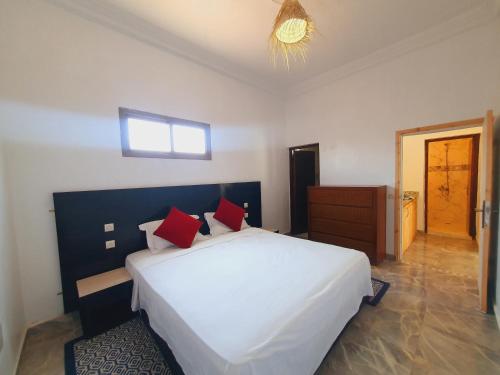 a bedroom with a large white bed with red pillows at Riad Elbahi in Marrakech