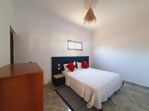 a bedroom with a white bed with red pillows at Riad Elbahi in Marrakech