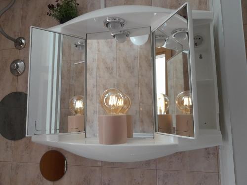 a bathroom with a mirror and lights on a wall at Studio Silvana & Room Renata in Lumbarda