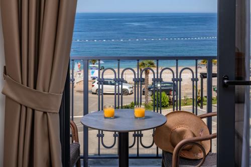 a table with two drinks on a balcony with a view of the beach at Wave Apartments - Dobra Voda in Bar