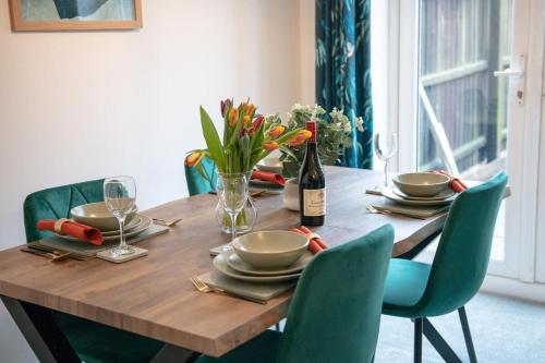a wooden table with chairs and a bottle of wine at 4-Bed, Sleeps 6, contractors welcome! in Peterborough
