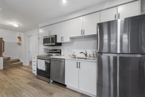 a kitchen with white cabinets and a stainless steel refrigerator at Luxury 2BR 2BTH Suite 5 Mins to The Falls Sleeps 6 in Niagara Falls