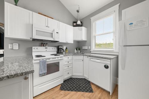 a white kitchen with white appliances and a window at The Rushes - 47 Butternut in Cherry Valley