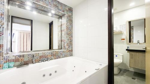 a white bathroom with a tub and a toilet at Hotel BE Suites Cali in Cali