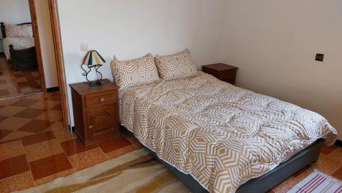 a bedroom with a bed and a lamp on a night stand at Douira Nature in Douaïra