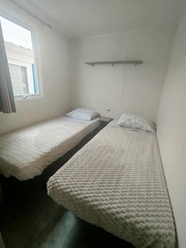 two beds in a small room with a window at Casinhas Do Alentejano - Lands house Bungalows in Burinhosa