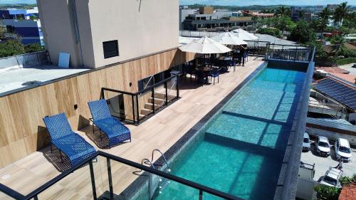 a swimming pool with chairs and umbrellas on a building at Porto Kai Residence Flat Vila de Porto de Galinhas 50m do mar in Porto De Galinhas