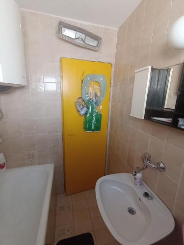 a bathroom with a yellow door and a sink at Vesela vila in Sutomore