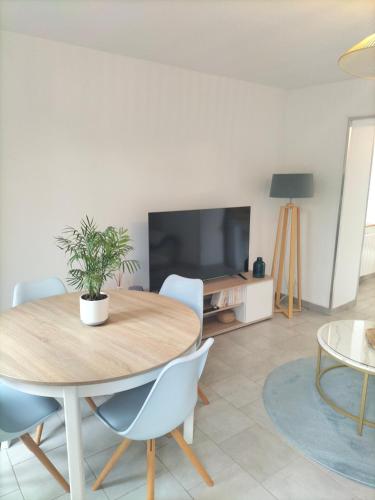 a dining room with a table and a tv at Appartement avec cour privée in Caen
