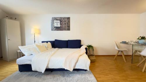 a bedroom with a bed with white sheets and a table at Boho Bliss Apartments in Delémont