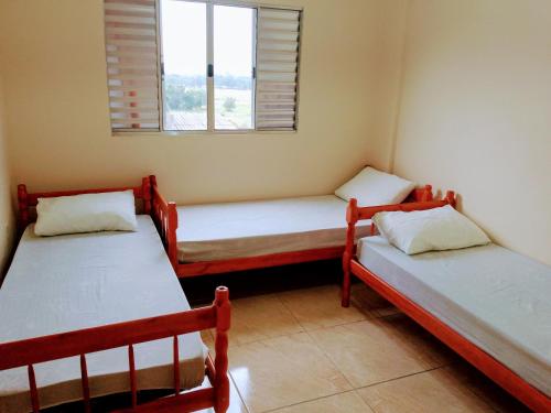 two twin beds in a room with a window at Bem Estar5 in Aparecida